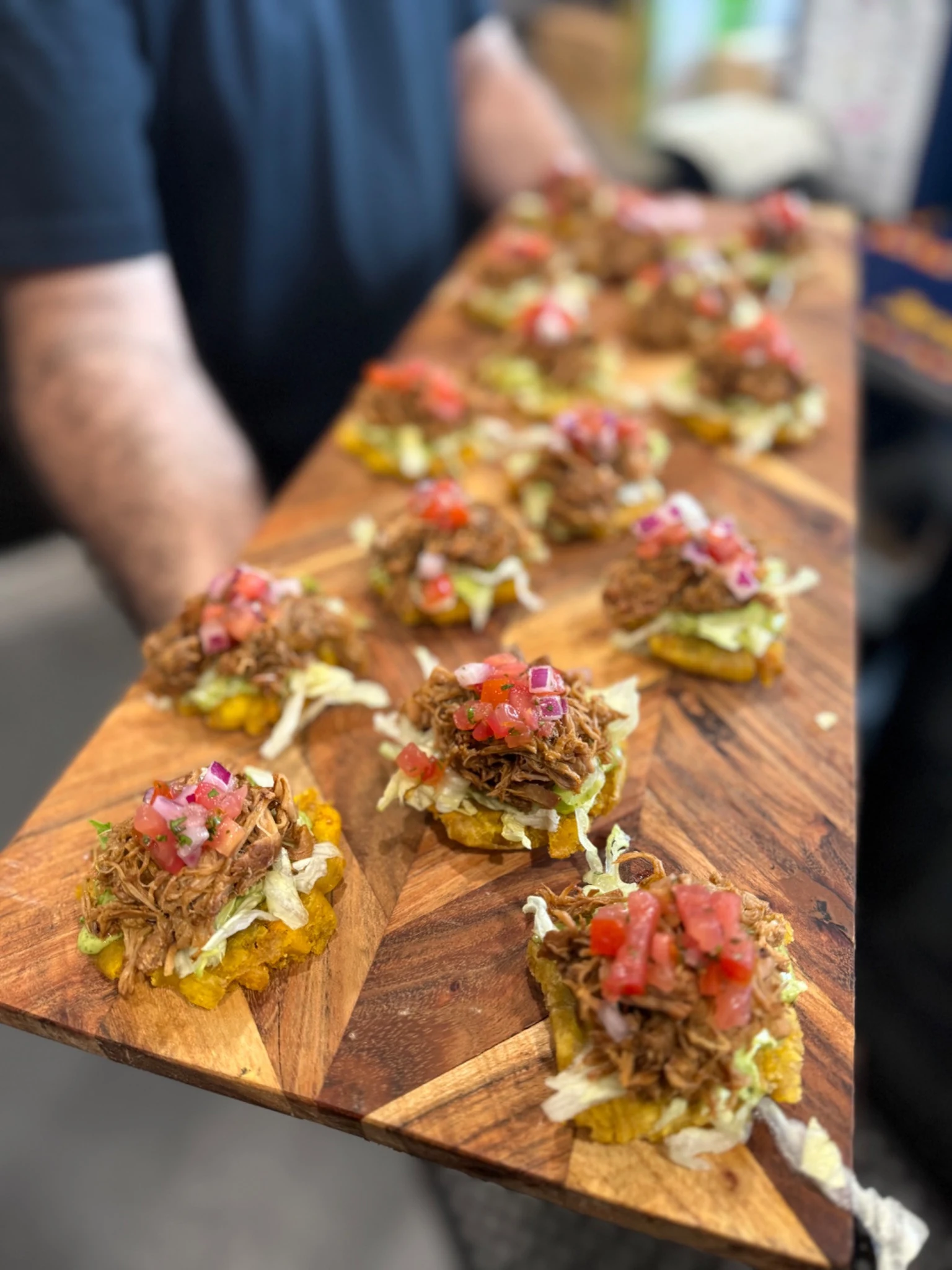 Bite-sized topped food arranged on a wooden serving board