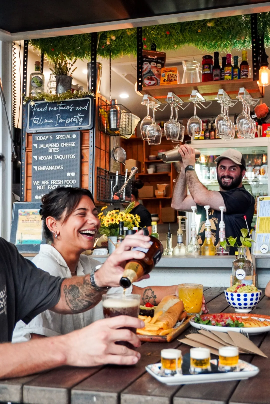 Guests laughing over food and drinks at El Bigoton while the team serves behind the bar