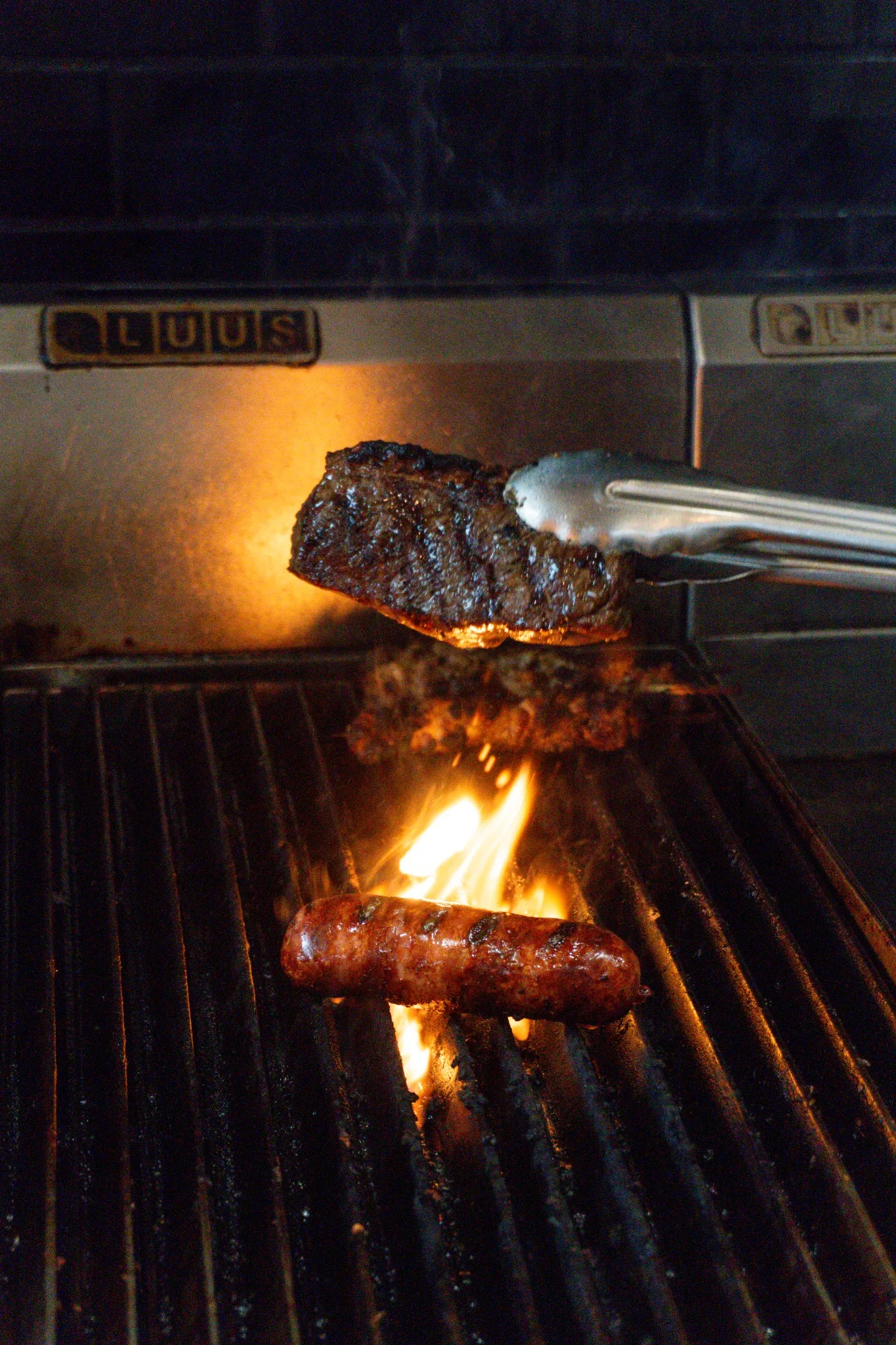 Picanha and sausage cooking over flame on the El Bigoton grill